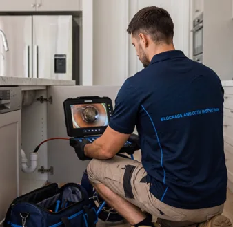 Plumber clearing a blocked toilet in a Bexley bathroom